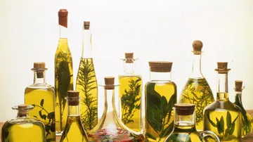 Oil bottles with herbs are on a table.