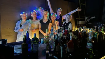 Gruppe von Frauen feiert vor einer Bar mit Glühlichtern.