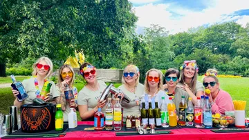 Group of women bartending outdoors in a park.