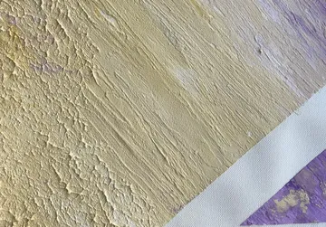 Texturierte Wandoberfläche in Gelb, mit lila Akzenten.