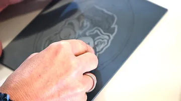 A hand edits a graphic drawing on a plate.