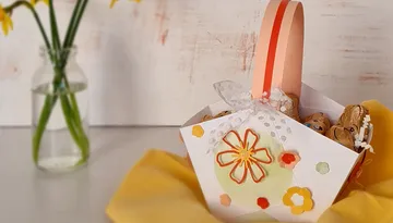 Buntes Osternest mit Süßigkeiten auf einem gelben Tuch.