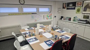 A table with painting supplies in an art room.