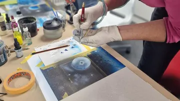 Eine Person sprayt kreative Farben auf eine Leinwand.