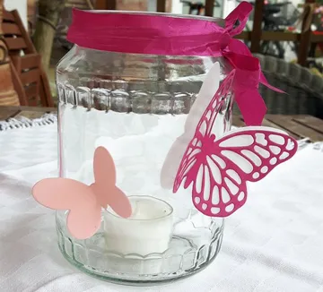 Glass jar with candle decorated with colorful butterflies.