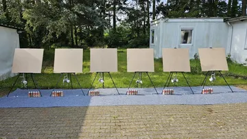 Canvases stand on stands, ready for use, outdoors.