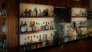 Shelf with various spirits, illuminated in a bar.