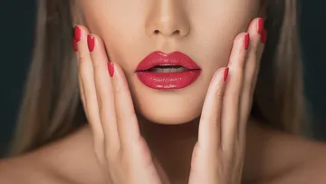 Rote Lippen und Hände umrahmen das Gesicht einer Frau.