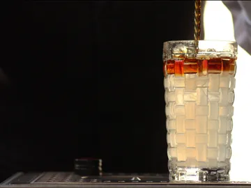 Glass is filled with liquid, dark background.