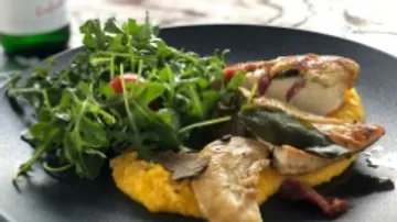 Hühnchen auf Polenta mit Rucola und Kirschtomaten serviert.