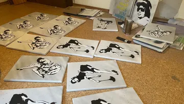 Canvases with stylized figures lie on the floor.