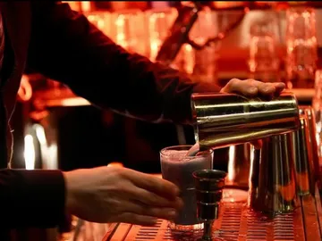 Bartender pours a drink into a glass at the bar.