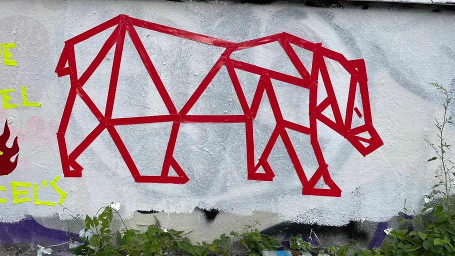 Red geometric bear mural on white wall.