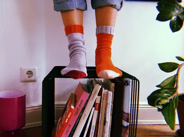 Colourful socks are on a bookshelf in a room.