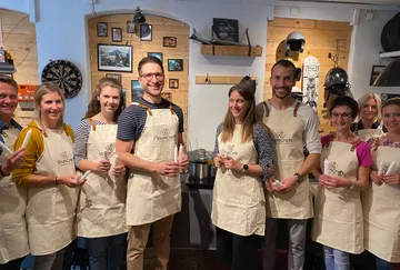 Group in aprons holding candles in a workshop.