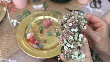 Getrocknete Blumen werden arrangiert, während ein Tisch dekoriert ist.