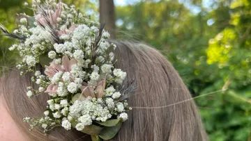 Blumenhaarreif ziert langes, braunes Haar im Freien.