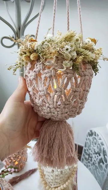 Hängende Vase mit Trockenblumen in behäkeltem Halter.