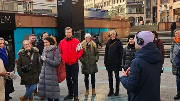Gruppe von Menschen hört einem Sprecher im Freien zu.