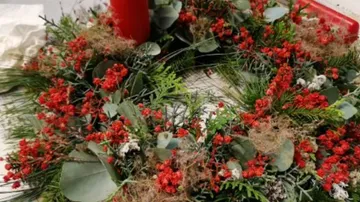 Ein Adventskranz mit roten Beeren und einer Kerze.