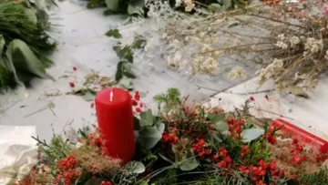 Roter Kerze steht in einem Kranz aus frischen Pflanzen.