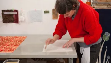 Eine Person arbeitet an einem Tisch mit Papier.