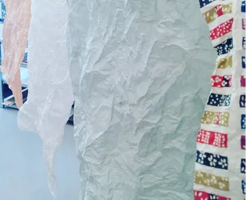 Zerrissene Papierstücke hängen in einem hellen Raum.