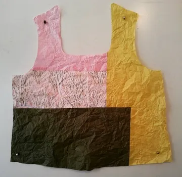 A colorful, wrinkled piece of textile hangs on a wall.