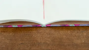Aufgeschlagenes Buch liegt auf Holzoberfläche, Lesezeichen sichtbar.