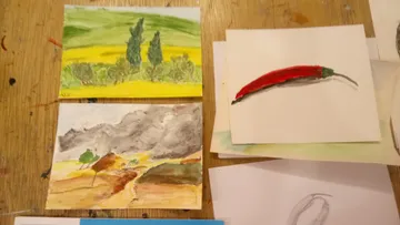 Gemalte Karten zeigen Landschaften und einen roten Chili.