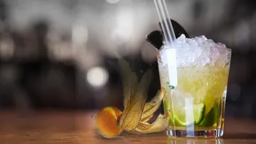 A glass with ice and a cocktail is on the table.