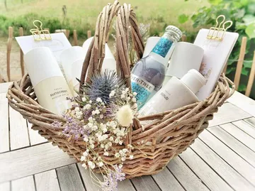 Ein Korb mit Pflegeprodukten und Trockenblumen auf einem Tisch.