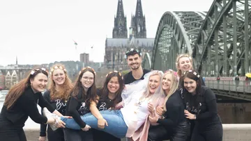 Group of friends celebrate hen party in front of bridge.