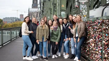 Gruppe von Frauen posiert neben einem Liebesschloss-Zaun.
