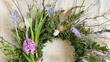 Decorative wreath of green leaves, flowers and eggs