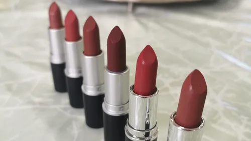 Six lipsticks stand in a row on a table.