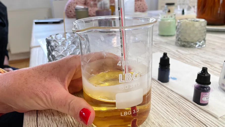 One hand holds a beaker with yellow liquid.
