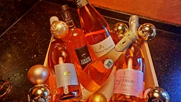 Flaschen Roséwein in einer dekorativen Box mit Weihnachtskugeln.