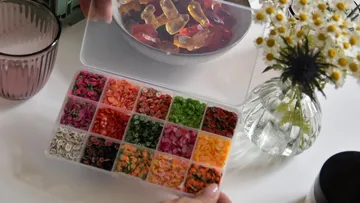 Colourful decorative elements are held over a bowl of gummy bears.