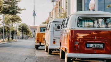 Colourful VW buses are parked on a street in Berlin.