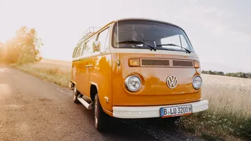 Ein orangefarbener Volkswagen-Bus steht auf einer Landstraße.