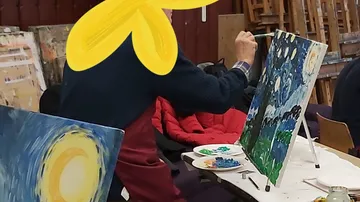A man is painting on canvas in a studio.
