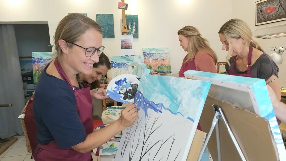 Vier Frauen malen in einem hellen Kunststudio gemeinsam.