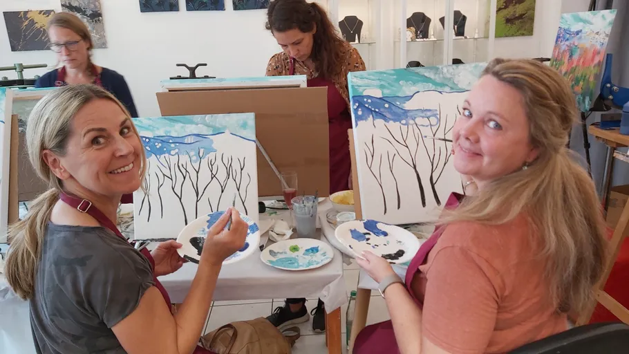 Zwei Frauen malen an Leinwänden in einem Kunststudio.