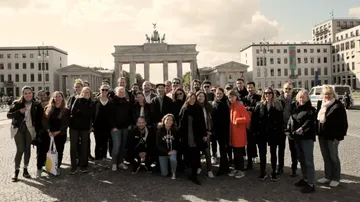 Group of people pose in front of the Brandenburg Gate.