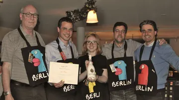 Five people with certificate and bottle in a Berlin pub.