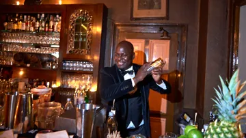 Bartender schüttelt Cocktails an einer gut gefüllten Bar.