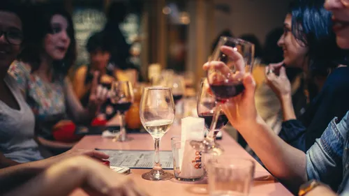 Women drink wine and talk in a restaurant.