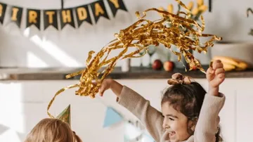 A girl swirls golden confetti in a party setting.