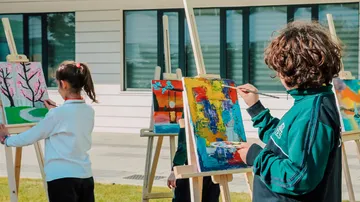 Children paint on outdoor easels.